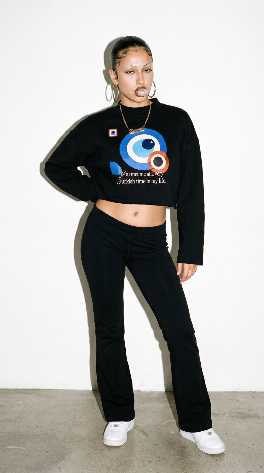 Frau mit Creolen im schwarzen Boxy Sweatshirt mit Nazar-Print, Studio mit Blitz
