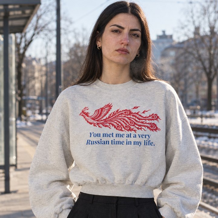 Frau am Bahnsteig im oat-grauen Cropped Sweater mit rotem Feuervogel