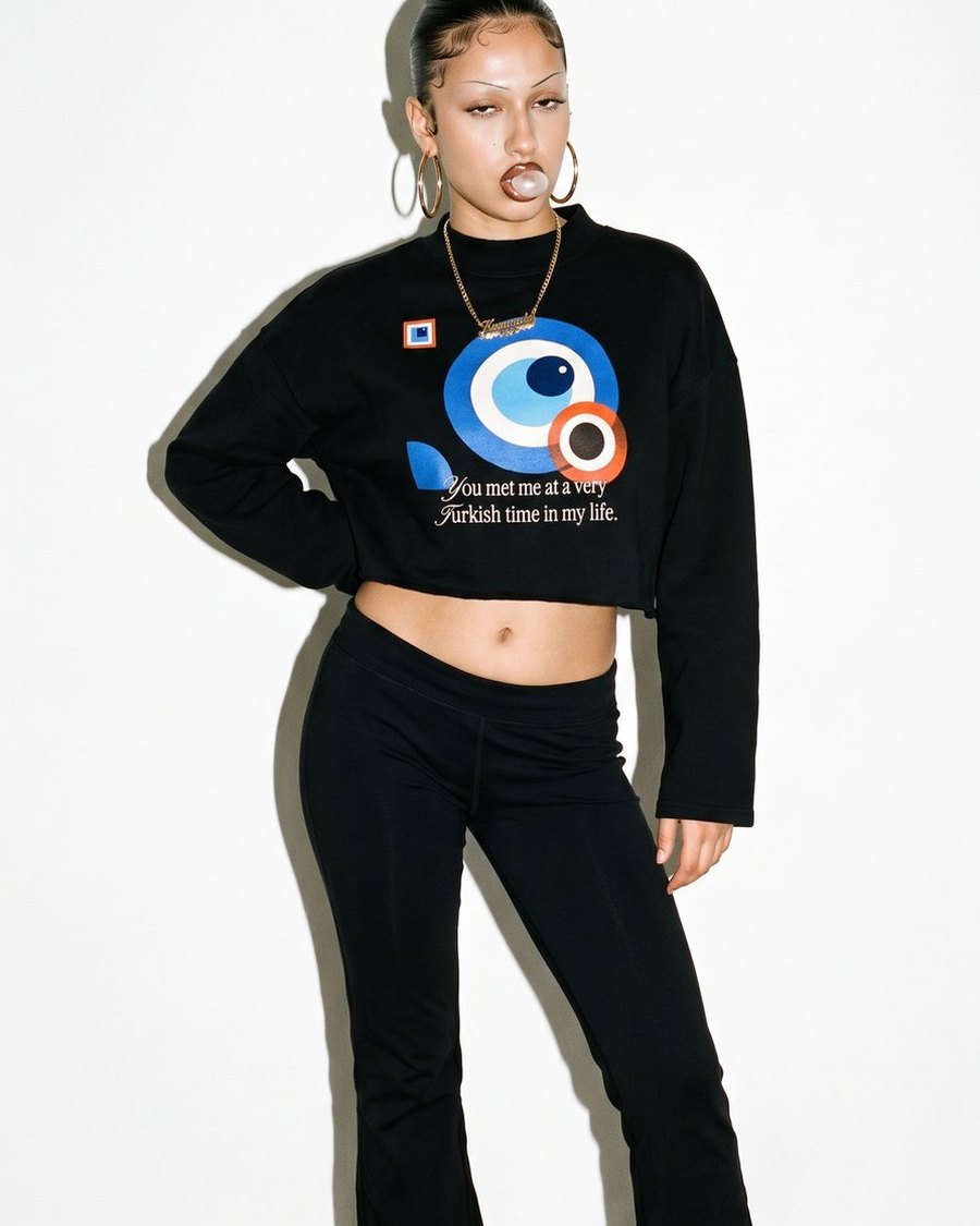 Frau mit Creolen im schwarzen Boxy Sweatshirt mit Bauhaus-Nazar-Print, Studio mit Blitz